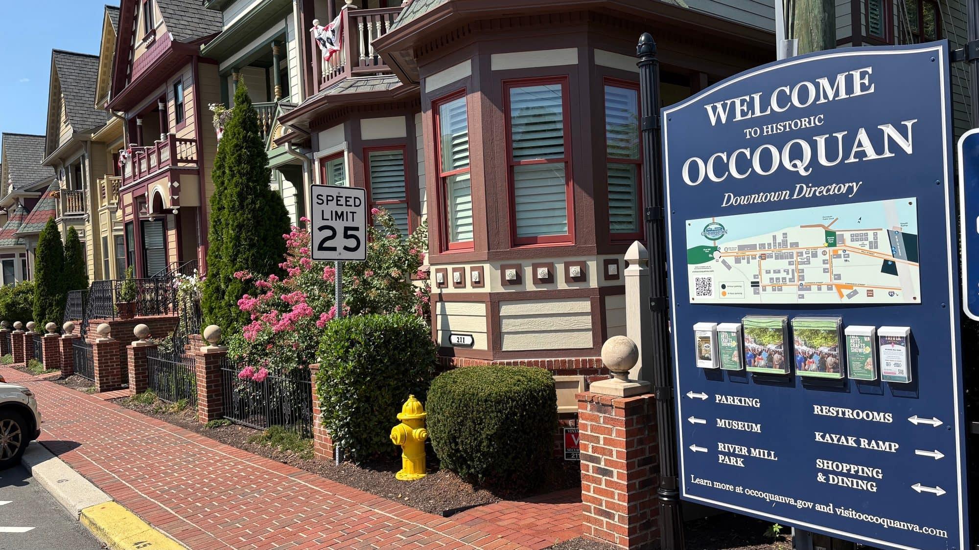 A 'Welcome to Historic Occoquan' downtown directory sign beside a charming Victorian storefront row